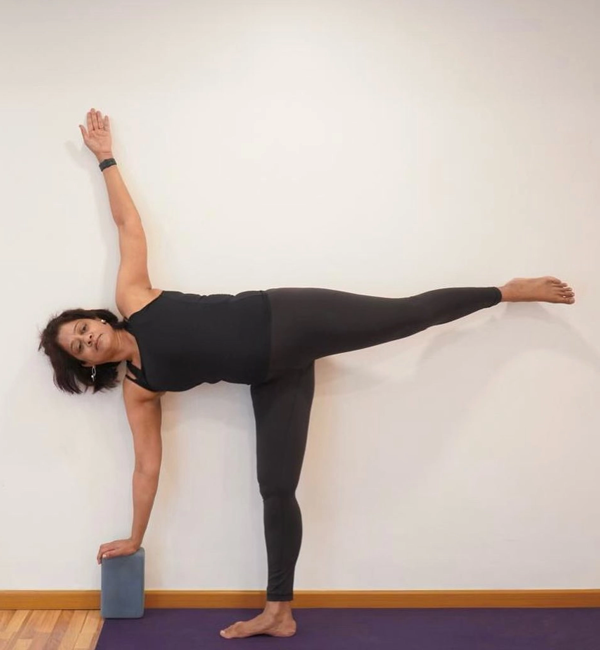Sharmila practicing a yoga pose against a wall
